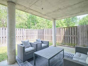 A covered patio area with wicker furniture, including sofas and a table.