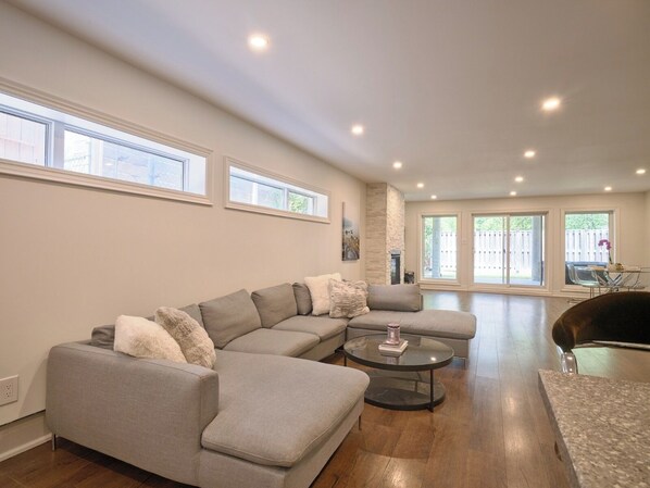 A modern living room with a sectional sofa, a round coffee table, and a dining area with a glass table.