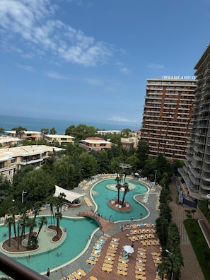 A resort with a large pool area, multiple lounge chairs, and a view of the ocean.