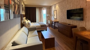 Una sala de estar moderna con sofá, mesa de centro, televisor y un comedor con sillas y una mesa.