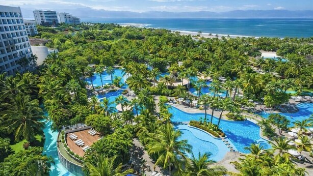 A resort with multiple swimming pools surrounded by palm trees and a view of the ocean. - Luxury Retreat at The Grand Mayan – Nuevo Nayarit (Nuevo Vallarta)