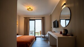 Une chambre d’hôtel avec un lit, un bureau doté d’une bouilloire, une télévision et une grande fenêtre.