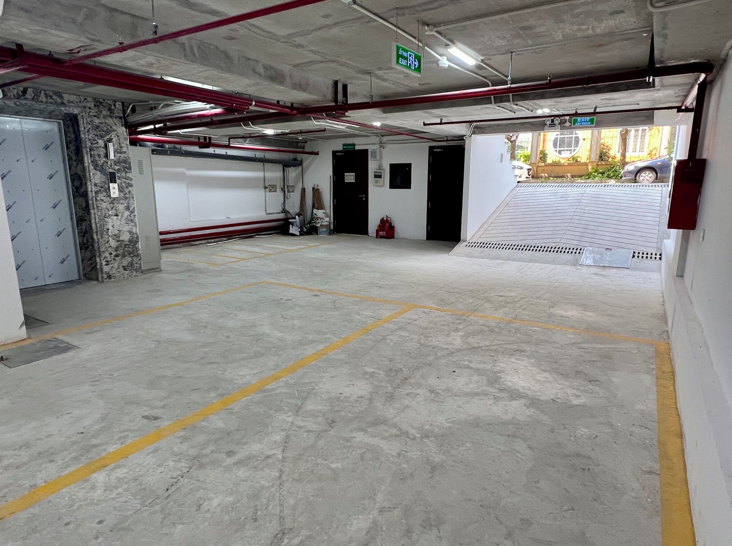 Un parking avec des planchers en béton, des emplacements de stationnement délimités et des panneaux indicateurs de sortie.