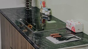 A kitchen counter with a sink, a vase with sunflowers, and various kitchen items. - Compact Studio w/ Projector & Sky View (Hà Nội)
