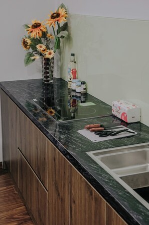 Uma bancada de cozinha com uma pia, um vaso com girassóis e diversos utensílios de cozinha.