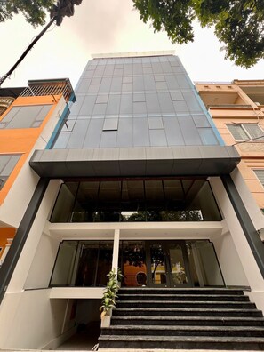 A modern building with a flat roof, large windows, and a staircase leading to the entrance. - Studio nhỏ xinh cho 1-2 người với đầy đủ tiện ích! (Hà Nội)