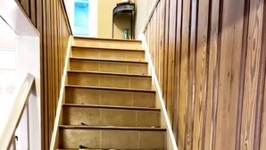 A wooden staircase with a handrail, a small table with a vase, and a view of a room with a window. - Historic Colonial Place by the River (Norfolk)