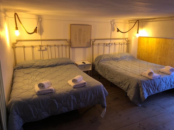 Two single beds with headboards, bedside tables, and a wooden headboard wall.