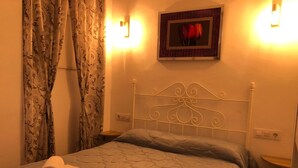Een slaapkamer met een bed, twee nachtkastjes, een aan de muur hangend fotolijstje, en een gordijn met een bloemenmotief.