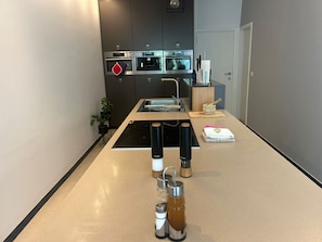 A modern kitchen with a central island, built-in oven, and a sink.