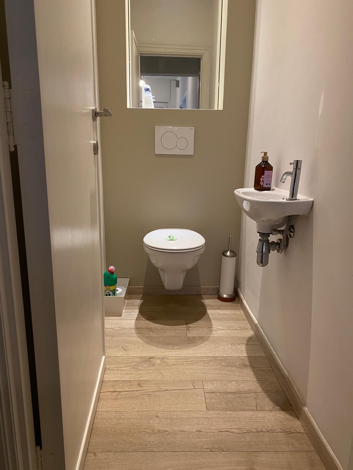 Une petite salle de bain comprenant des toilettes, un lavabo et un miroir.