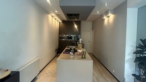 A modern kitchen with built-in appliances, a central island, and a hallway leading to a door.