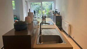 A modern kitchen with a large window, a sink, and a countertop with a potted plant.