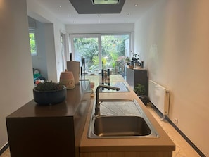 A modern kitchen with a large window, a sink, and a countertop with a potted plant.