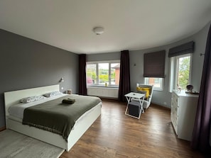A bedroom with a bed, a small table, a chair, and a dresser.