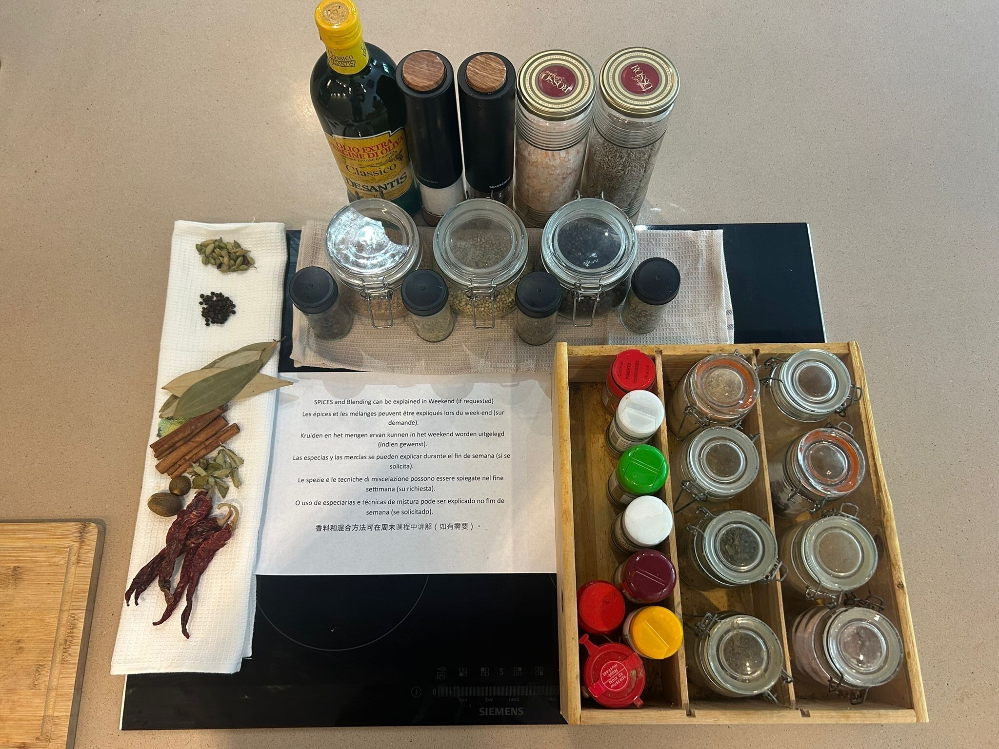 A kitchen counter with various spices, jars, and a bottle of oil.