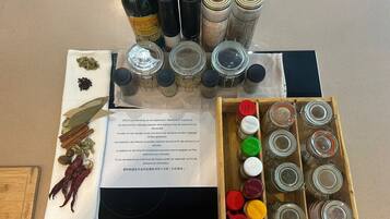 A kitchen counter with various spices, jars, and a bottle of oil.