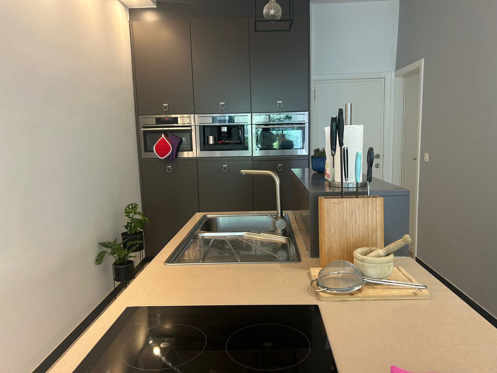 A modern kitchen with a built-in oven, microwave, and stainless steel sink.