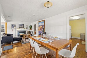 A dining area with a wooden table, white chairs, and a fireplace. - Route 66/Grand Canyon Retreat, Central Williams, Family-friendly, Sleeps 8 (Williams)