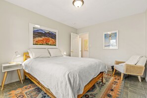 A bedroom with a bed, a nightstand, a chair, and two framed pictures on the wall. - Route 66/Grand Canyon Retreat, Central Williams, Family-friendly, Sleeps 8 (Williams)