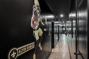 En gang med et stort plakat af en fodboldspiller, et skilt med 'ALVIN KAMARA' og en dør med påskriften 'SAINTS'.