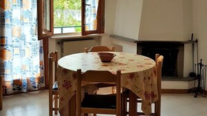 A dining room with a round table, chairs, a fireplace, and a clock on the wall. - Apartment with fireplace and view of the Orfento Valley (Caramanico Terme)