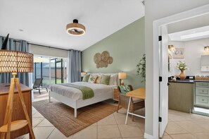 Ein Schlafzimmer mit Bett, Nachttisch, Lampe und Blick ins Freie.