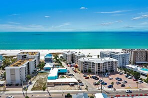 Ein Küstenhotel mit mehreren Gebäuden, einem Parkplatz und einem Strand im Hintergrund.