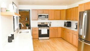 Een moderne keuken met houten kastjes, roestvrijstalen apparatuur en een bakstenen muur.