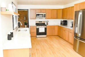 Eine moderne Küche mit Holzschränken, Edelstahlgeräten und einer Ziegelwand.