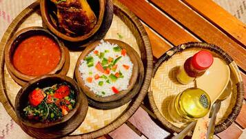 Una mesa de madera con varios platos, incluyendo arroz, sopa y un muslo de pollo a la parrilla.