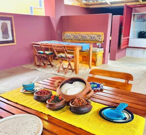 Un comedor con una mesa preparada para dos personas, que incluye un tazón de comida blanca, un tazón azul y varios platos pequeños con comida y especias.