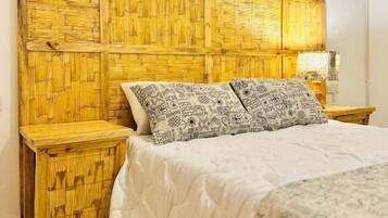 Een kamer met een bed, nachtkastje, een decoratief object aan de muur en een geweven hoofdbord.