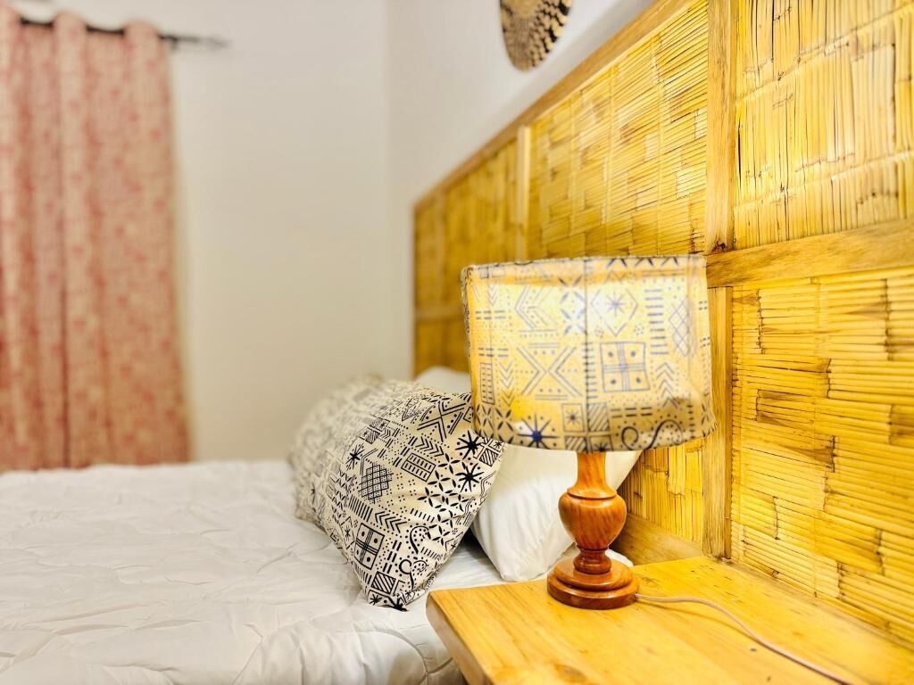 A bed with patterned pillows, a wooden bedside table, and a bamboo headboard.
