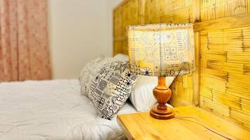 A bed with patterned pillows, a wooden bedside table, and a bamboo headboard.