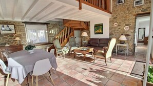 Un vaste espace de vie comprenant une table à manger, plusieurs chaises, un canapé et un escalier menant à un niveau supérieur.