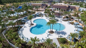 An aerial view of a resort with a large central pool, surrounded by palm trees and lounge areas. - TIFFANYS VILLAS Solara (Kissimmee)