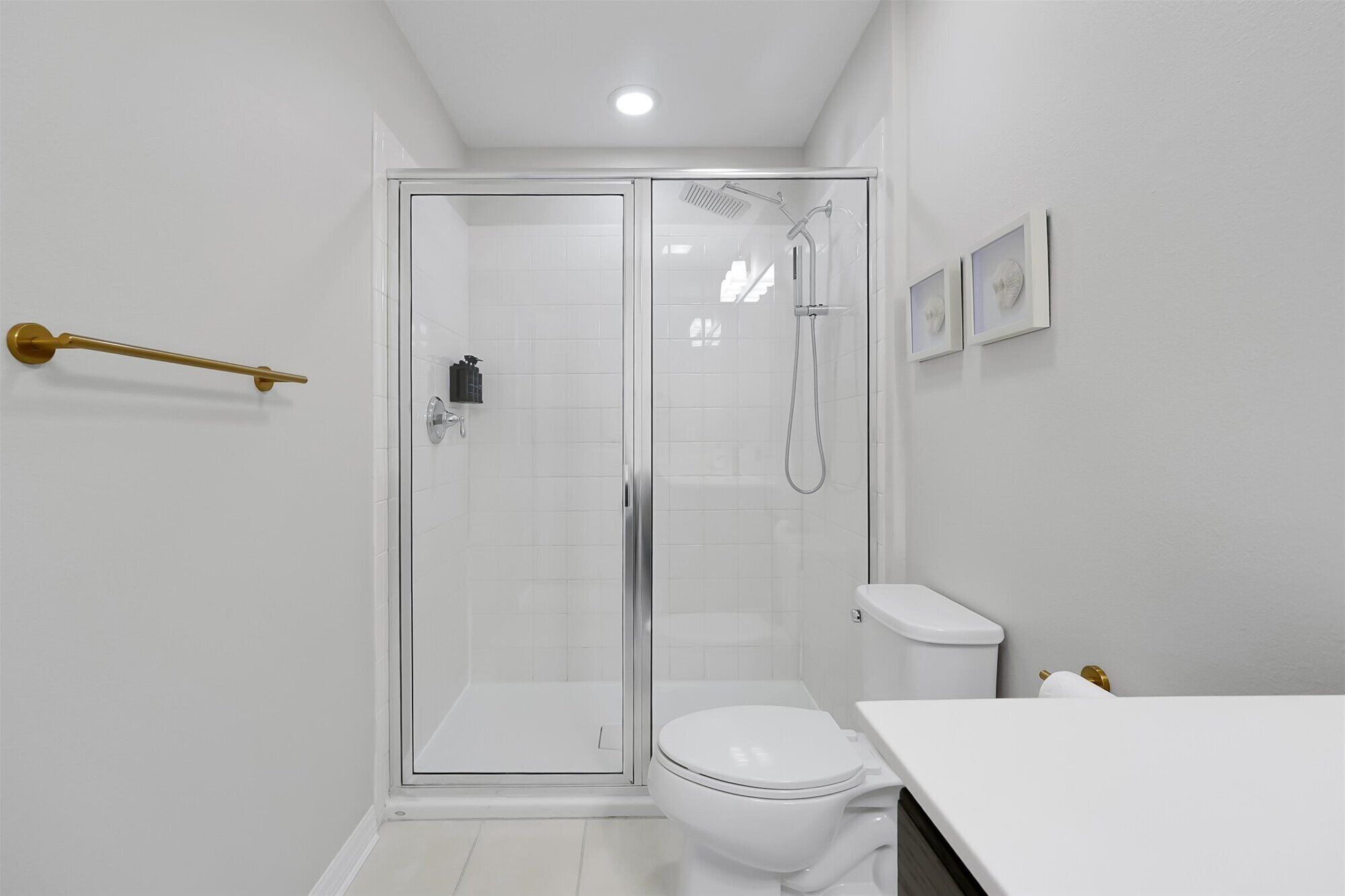 Ein modernes Badezimmer mit einer Glaskabine zur Dusche, einer weißen Toilette und einem weißen Waschbecken.