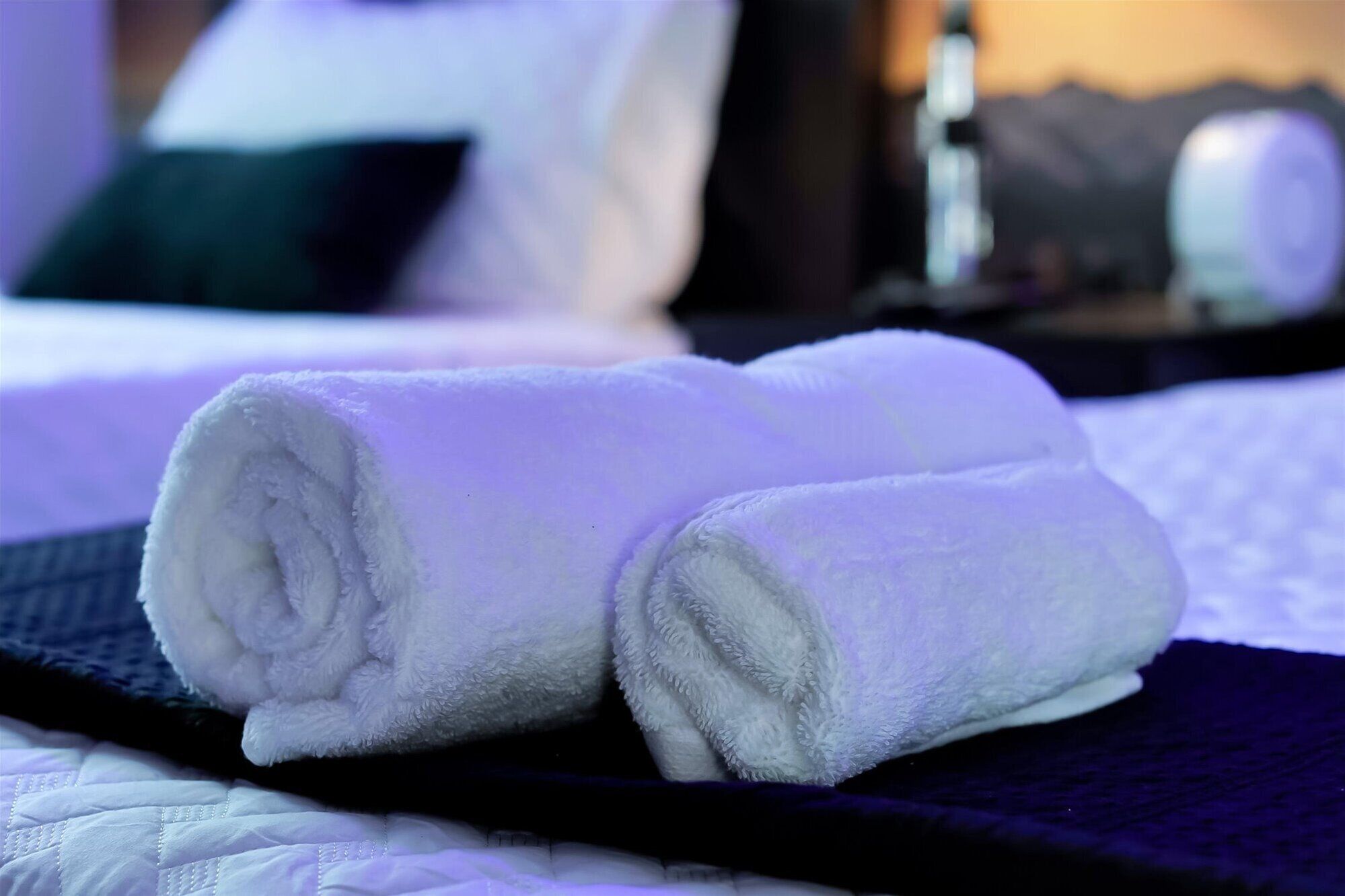 A neatly made white towel on a bed with a dark blue headboard and white bedding.
