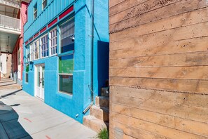 Une rue étroite avec un bùtiment bleu et un mur en bois.