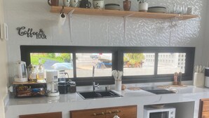 Een keuken met een koffiebar, een magnetron en een spoelbak.