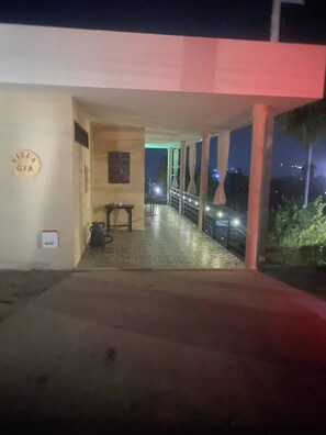 Ein überdachter Außenbereich mit Tisch und Stühlen, einem an der Wand befestigten Schild und Blick auf den Nachthimmel.