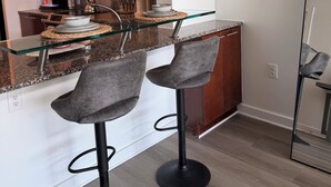Una cucina moderna con un'isola in vetro, mobili in legno scuro e un forno a microonde in acciaio inossidabile.