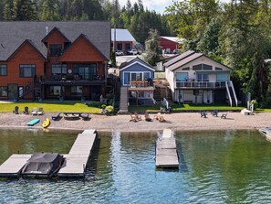 A lakeside property with multiple buildings, a dock, and a grassy area with outdoor seating. - Little Hamptons on The Lake (Newport)