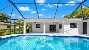 Ein modernes Poolhaus mit einem klaren, blauen Pool, weißen Außenwänden und einer Metall-Dachkonstruktion.
