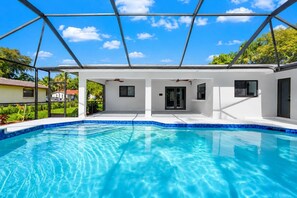 A modern pool house with a clear blue pool, white exterior walls, and a metal roof structure. - Coral Springs Oasis Retreat (Coral Springs)