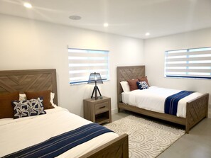 Une chambre avec deux lits, une table de chevet, une lampe et un tapis à motifs.