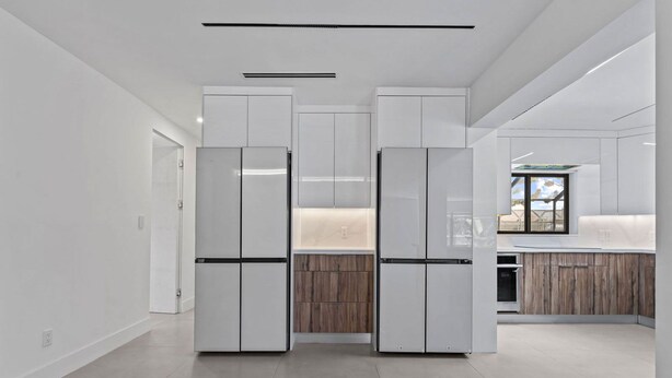 Eine moderne Küche mit weißen Schränken, einer Holz Arbeitsplatte und einem eingebauten Backofen.