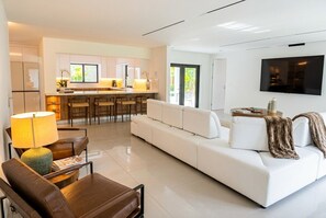 A modern living room with a white sofa, a coffee table, and a TV mounted on the wall. - Coral Springs Oasis Retreat (Coral Springs)