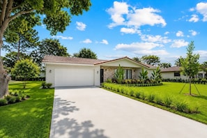 A single-story house with a garage, surrounded by a well-maintained lawn and trees. - Coral Springs Oasis Retreat (Coral Springs)